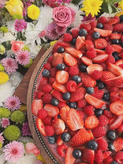 A vibrant mixed berry dessert surrounded by a bed of fresh, colorful flowers. I love creating beautiful displays for family and friends.