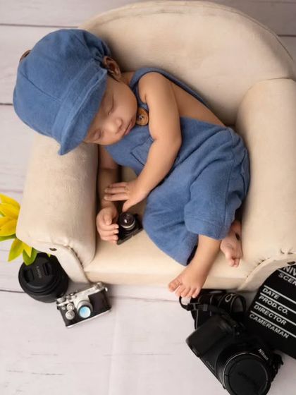 A different angle of the sleeping director, capturing the adorable details of his tiny outfit and the surrounding props.