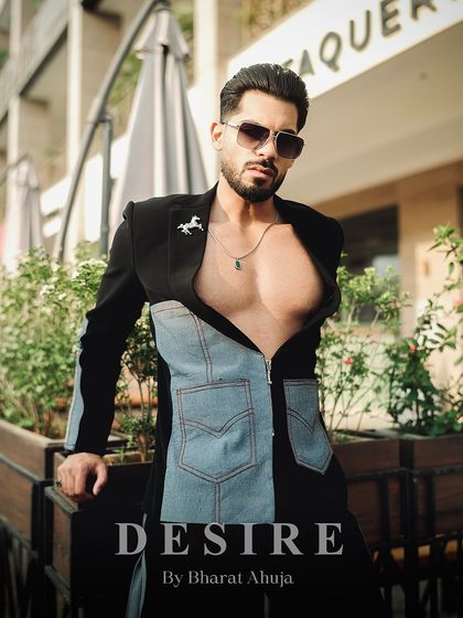 A full-body shot of the black and denim fusion jacket, worn open to reveal a confident physique. The horse brooch adds a signature touch of western luxury.