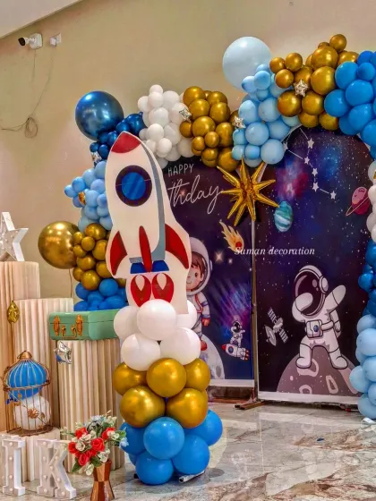 A side view of the space-themed decor, showing the rocket ship cutout and how the balloon arrangement wraps around the backdrop to create a dynamic look.