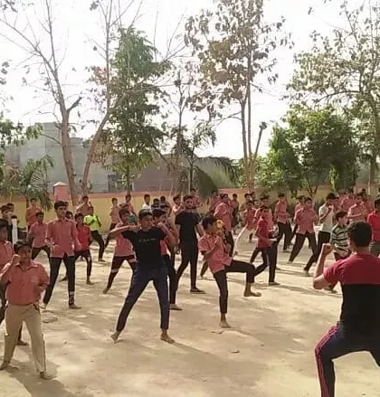 An instructor leads a large group of school students in basic karate stances during an outdoor workshop. Introducing martial arts to the community is a core part of our mission.