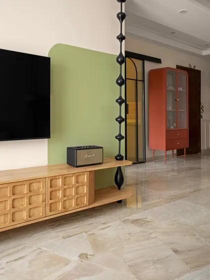 A close-up of the TV console, highlighting the carved wooden details and the Marshall speaker, a nod to classic design. The space is layered with contrasts, from muted backdrops to confident bursts of color.