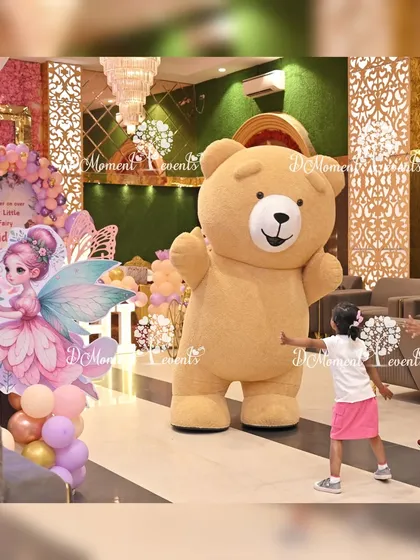 Kids love meeting their favorite characters. Here, a giant teddy bear mascot gives hugs and takes photos with the young guests at a fairy-themed party.