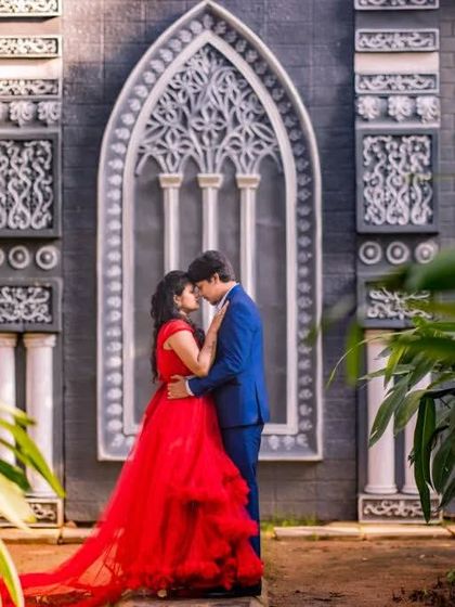 An intimate embrace in a beautiful architectural setting. The red gown and blue suit stand out, making the couple the clear focus of this romantic pre-wedding photo.