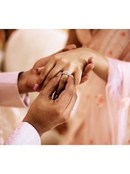 The pinnacle moment of an engagement ceremony, captured in a tight shot as the ring is placed on her finger.