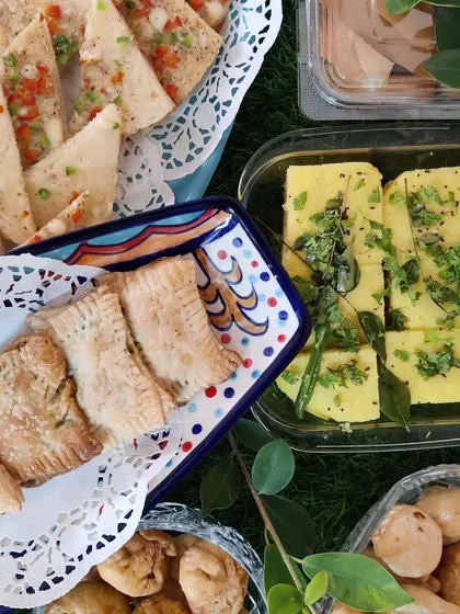 A glimpse of a high tea spread we catered, featuring our fresh, spongy Khaman Dhokla, savoury baked puffs, and other bite-sized Indian snacks.