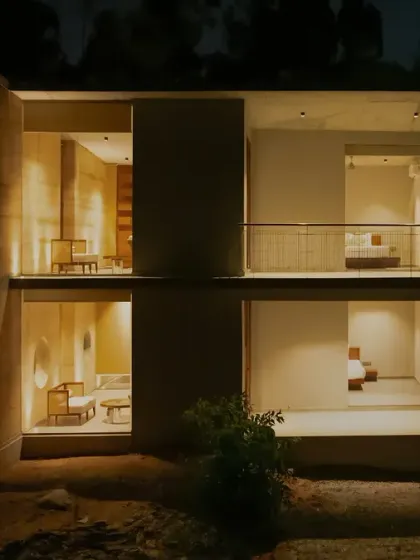 A night shot of a two-story resort block, showcasing the clean, stacked geometry and the warm, inviting glow from the rooms.