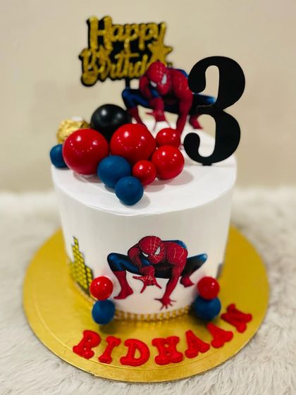 A dynamic Spider-Man cake for a third birthday. This design features the web-slinger in action poses, surrounded by red and blue spheres.