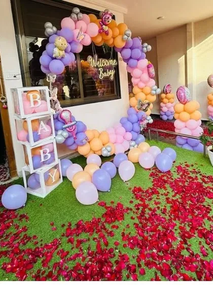 A grand 'Welcome Baby' entrance decoration with a balloon arch and a path of rose petals.