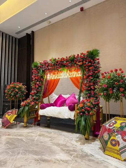 A wider view of the floral swing setup for a Mehendi ceremony. I placed it against a backdrop of colorful drapes and surrounded it with floral arrangements and traditional umbrellas, creating a complete and beautiful focal point for the event.