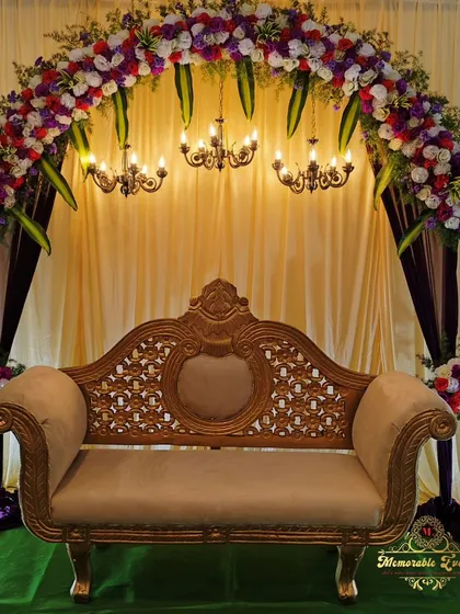 For a traditional baby shower, we created this stunning floral arch with rich purple and red flowers over an ornate carved sofa. The setup includes classic chandeliers and a fabric drape backdrop for a truly regal feel.
