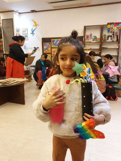 A proud young artist holds her completed New Year's party blower. These workshops are all about having fun and creating something special to mark the celebration.