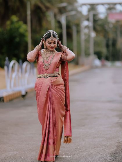 A full-length portrait of the bride, her pose elegant as she adjusts her traditional headpiece.