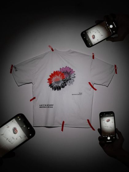 A creative concept for a t-shirt flat-lay. By surrounding the product with phones all taking its picture, the image playfully suggests that the design is "Insta-worthy" and trending.