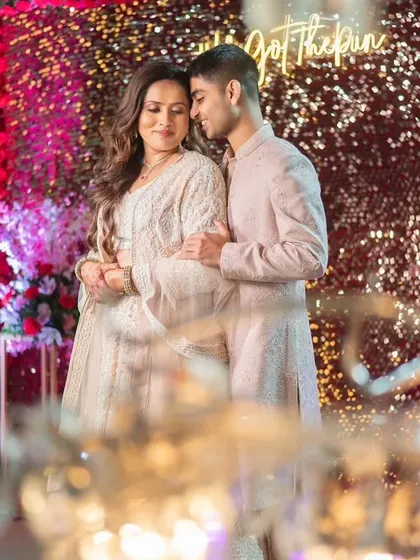 This couple's Sangeet look is pure elegance. The bride's makeup is soft and glowing, with her hair in romantic waves, perfectly matching the dreamy, fairy-light ambiance.