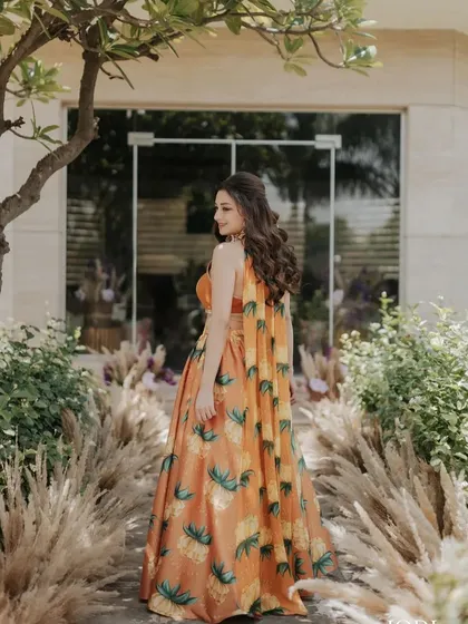 The back view of the client's half-up style, showing off her long, wavy hair against her beautiful floral lehenga.