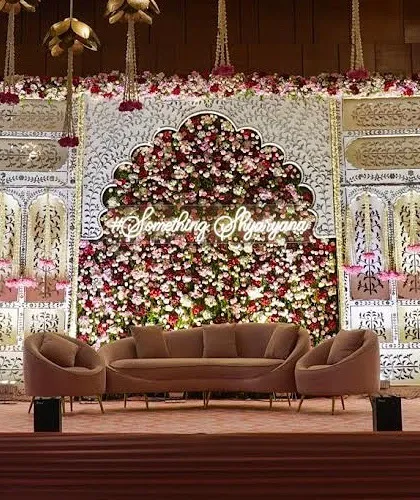 The full view of the engagement stage, showcasing the magnificent floral backdrop and the couple's custom hashtag. The blush-toned sofas provide a perfect spot for the couple during the ceremony.