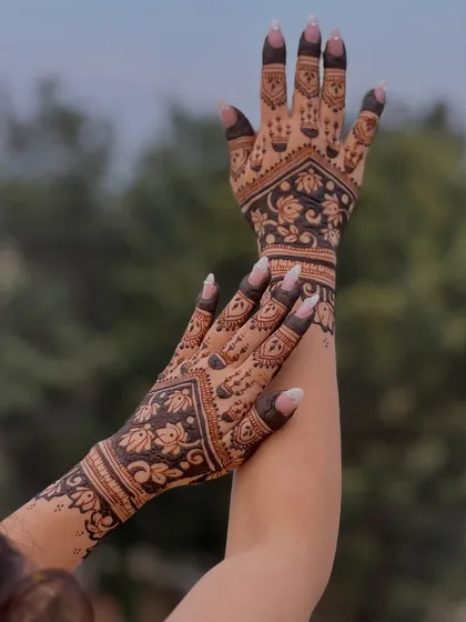 This is an example of a semi-bridal design that feels both traditional and modern. The use of negative space with the bold floral patterns on the back of the hand creates a striking look, perfect for any grand celebration.