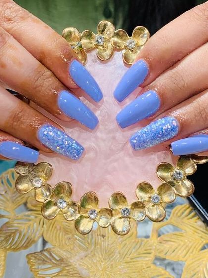 A lovely periwinkle blue set with a sparkling blue glitter accent nail on coffin-shaped extensions.