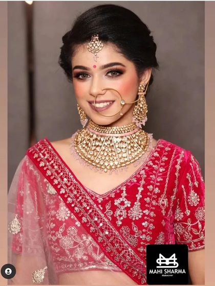 A smiling bride in a bright pink lehenga with intricate silver embroidery. The oversized Kundan choker from our rental jewellery collection makes a bold and beautiful statement.