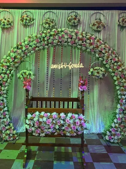 A beautiful naming ceremony setup where the wooden cradle is the star. The full floral arch in pink and white creates a soft and celebratory entrance for the baby.
