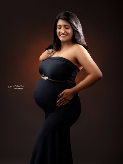 A timeless portrait in a black strapless gown, with a gentle smile that radiates pure joy and anticipation.