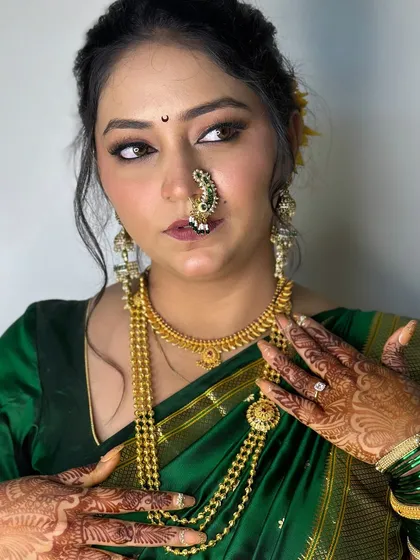 A close-up showcasing the details of a 'Vidhi' look. Notice the subtle smokey eye, the perfectly placed nath, and the glow that radiates from within, set against a traditional green saree.