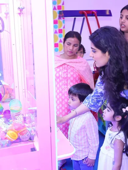 The claw machine is always a huge attraction. A mother and her children trying their luck to grab a prize during a fun-filled birthday party.