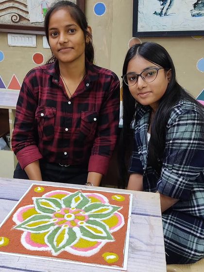 Two students with their completed floral rangoli. Our competitions often encourage teamwork and collaboration.