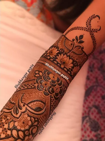 A detailed arm band with a mix of floral and paisley patterns. The design ends with a delicate leafy vine that trails up the arm, adding a touch of elegance.