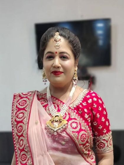 A traditional party look with a red bindi and classic red lipstick. The makeup is flawless and enhances her natural beauty, perfect for any festive gathering or wedding event.