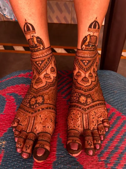 A classic bridal feet design with elephant motifs on the ankles and jhumka (earring) patterns below. The floral details on the toes complete the look.