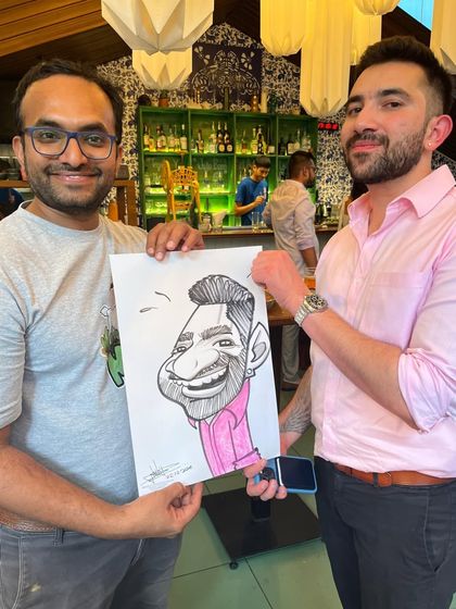 Posing with a guest and his caricature at the engagement party.