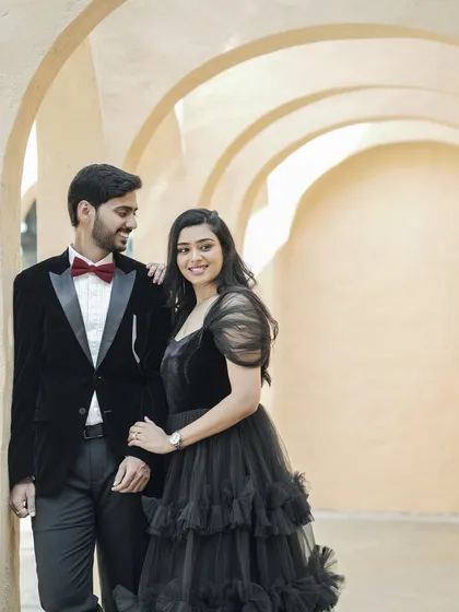 An elegant couple dressed in formal wear for their pre-wedding shoot. The groom in a velvet tuxedo and the bride in a black tulle dress create a sophisticated and classic look.