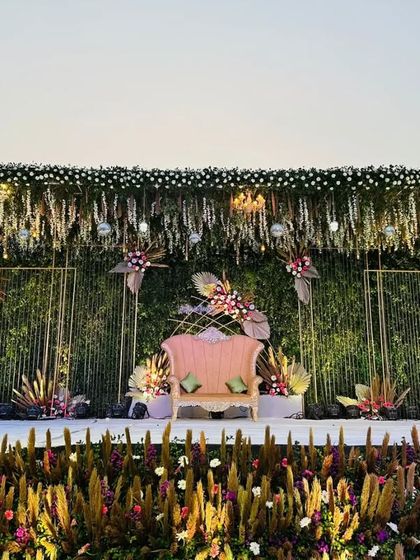 The same breathtaking stage seen in daylight, showcasing the intricate details of the floral arrangements and the contrast between the soft pampas grass and the structured green backdrop.