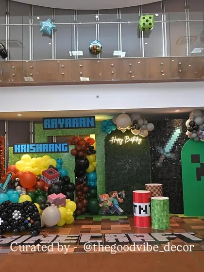 We built a complete Minecraft world for this 8th birthday bash. The setup included a pixelated green wall, character cutouts, and balloon arrangements shaped like game elements like TNT and controllers.