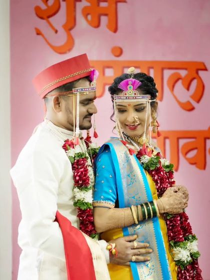 A lovely portrait of the couple in front of a "Shubh Mangal Savdhan" sign, a perfect wedding day memory.