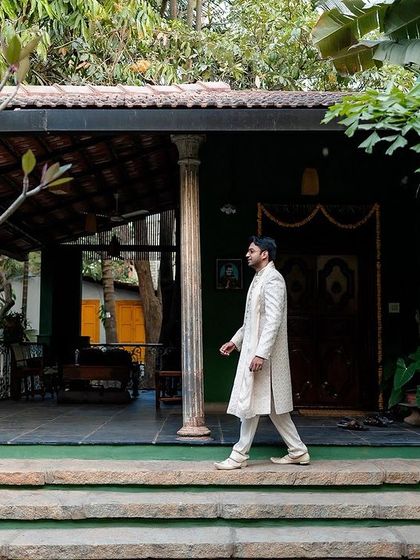 A stylish portrait of the groom as he walks through the venue. This candid-style shot captures his elegance and the beautiful, rustic ambiance.