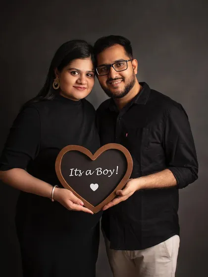 A classic studio portrait for a baby boy announcement. The dark backdrop and simple outfits create a timeless look for this special memory.