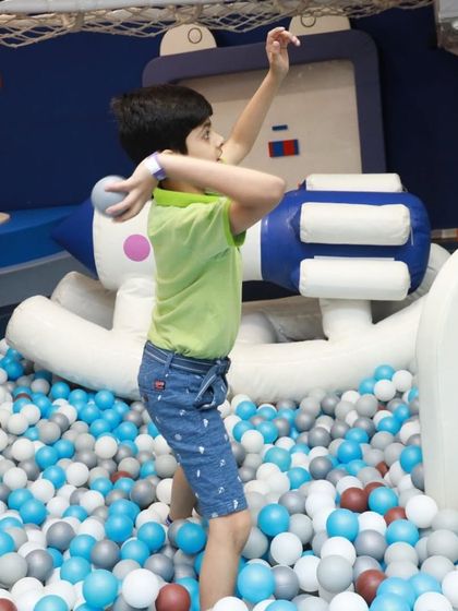 A young adventurer getting ready to throw a ball in our interactive play zone. The ball pit is filled with opportunities for active and imaginative play.