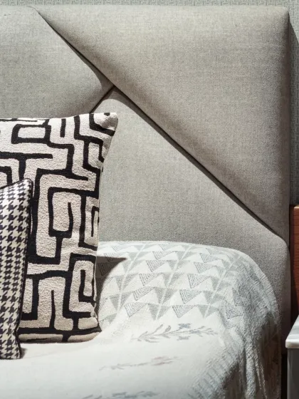 A close-up of the custom upholstered headboard in the Rue 32 master bedroom. The geometric pattern and textured fabric add a layer of sophistication and comfort, punctuating the room's serene, monochromatic palette.