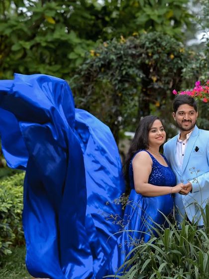 A beautiful shot of a flowing blue gown amidst the pink flowers of the garden.