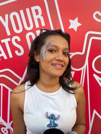 A happy client with a blue glitter design on her cheek. The color perfectly matches her Stitch-themed top.