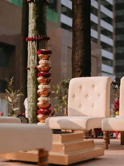 The seating for the couple and their parents, featuring elegant cream-colored chairs and traditional stacked copper pots.