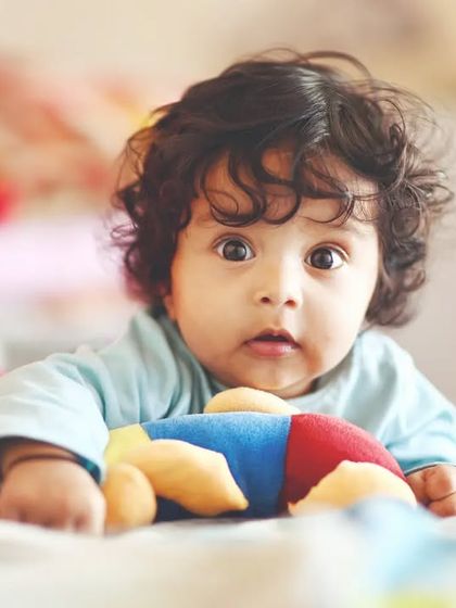 A bright-eyed baby with beautiful curly hair, captured during a moment of quiet curiosity. These simple, natural portraits are timeless.