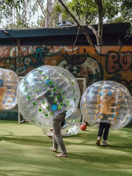 The back view of a Bubble Soccer game, showing players moving around the field in their giant bubbles.