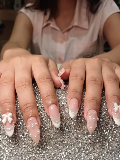 The perfect bridal or special occasion nails. This set features a classic French tip base adorned with delicate pearls and elegant white 3D bows.