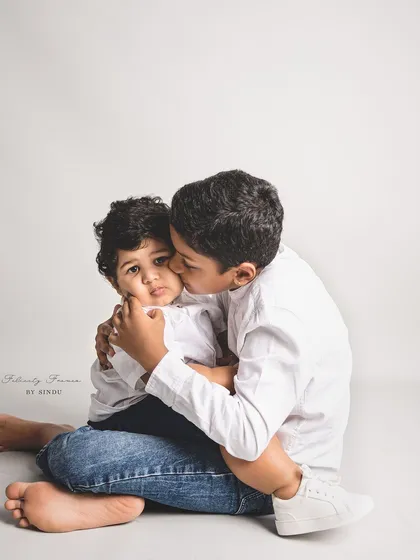 A tender moment between two brothers in the studio. The older brother wraps his arms around his younger sibling, showcasing a protective and loving bond.