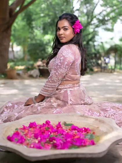 A creative shot from a model shoot, with the model sitting by a bowl of bougainvillea flowers, adding a pop of color to the scene.