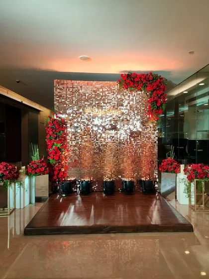 A wider view of the rose-gold sequin backdrop, showing the wooden stage and floral arrangements. This setup is perfect for photo opportunities or as a stylish background for a cake-cutting ceremony.